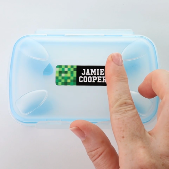 Stick-on name label being applied to a lunch box
