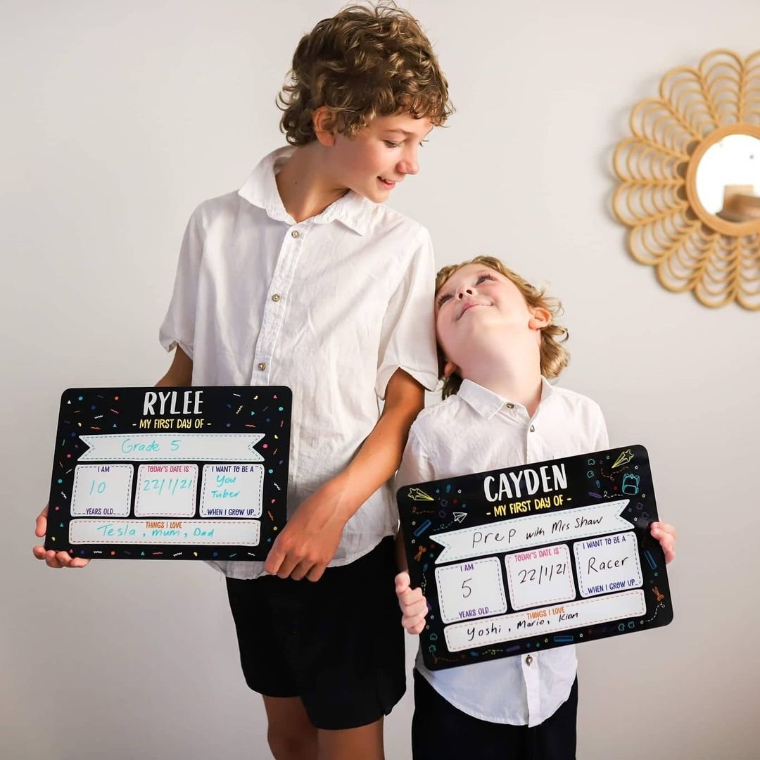 Two brothers holding personalised first day of school signs